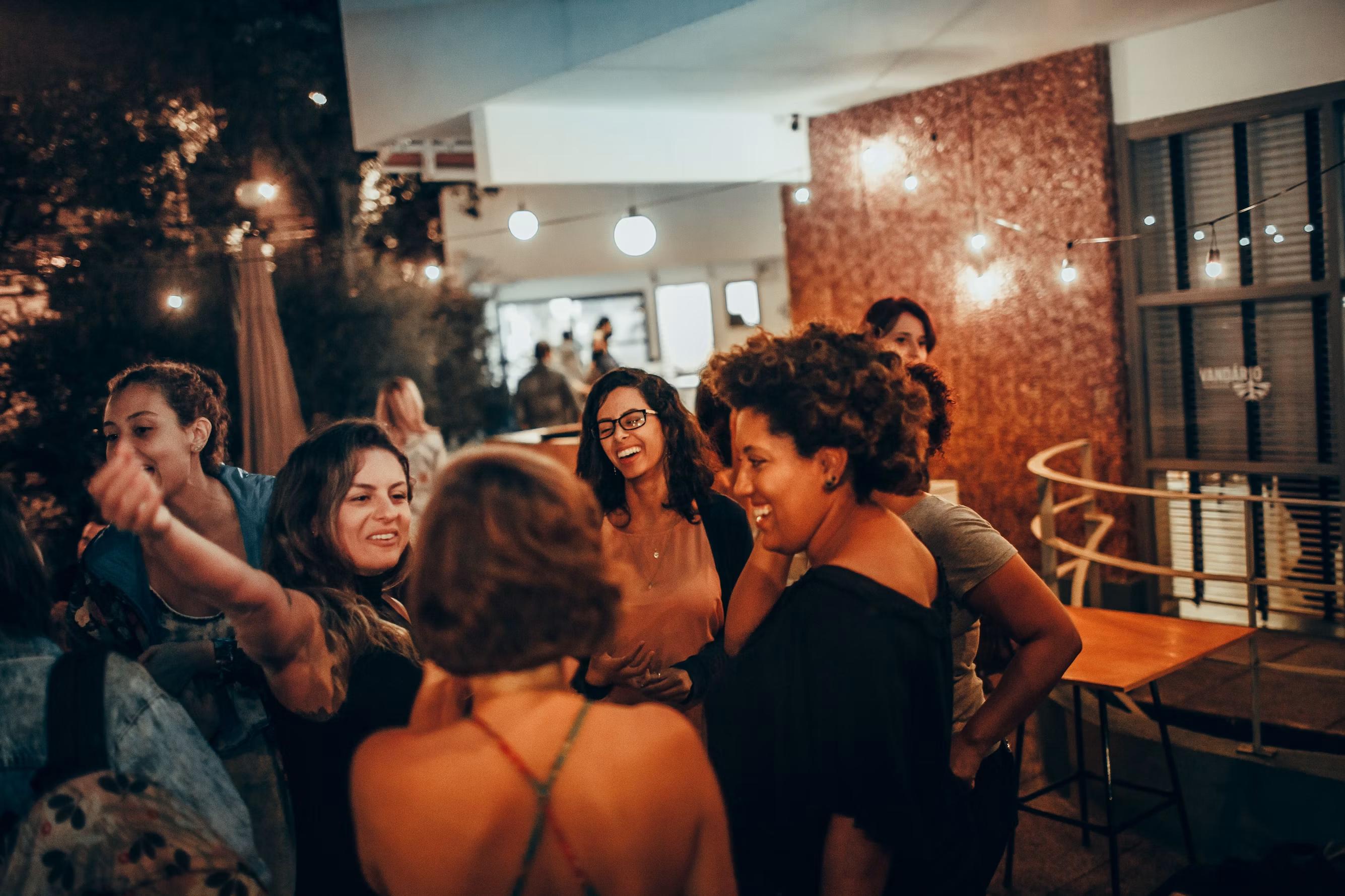 Guests mingling under string lights at a warm SoHo nightlife venue